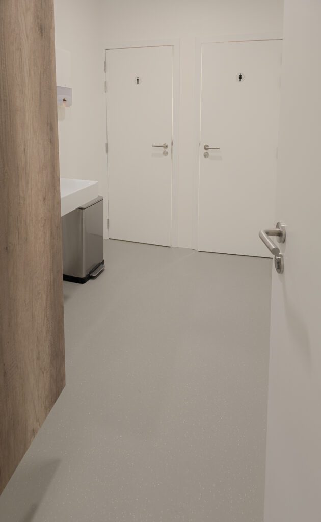 Volledig vernieuwde sanitaire ruimte met naadloze PU gietvloer en strakke witte wandafwerking.