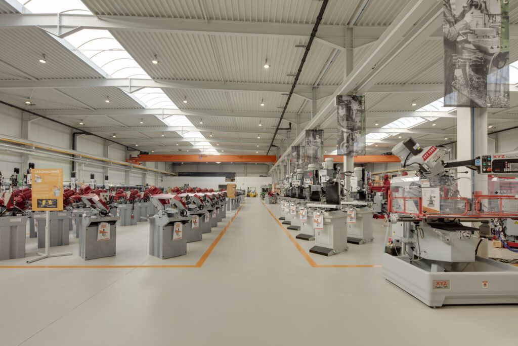 Overzicht van de volledige toonzaalvloer bij Crispyn met epoxycoating, PU-toplaag en oranje belijning op lichtbeige achtergrond